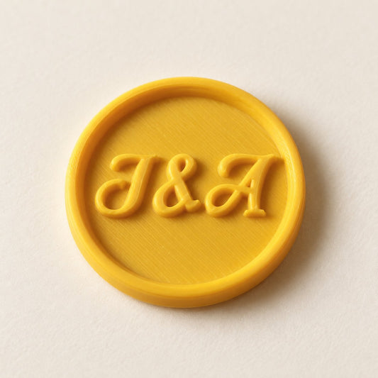 Detalle de un sello adhesivo redondo amarillo con iniciales J&A en relieve, acabado Minimal