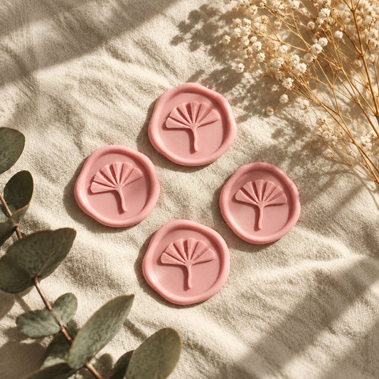 Cuatro sellos adhesivos de ginkgo en rosa con borde rústico sobre tela crema con eucalipto