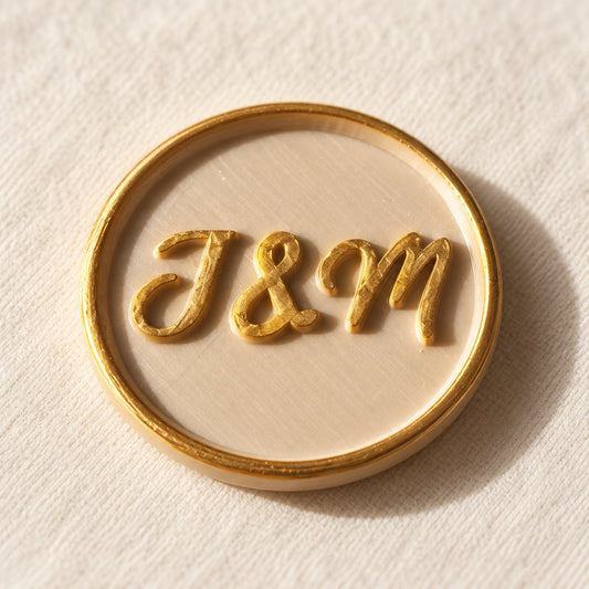 Detalle de un sello adhesivo arena con iniciales J&M doradas y borde dorado, acabado Signature