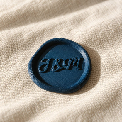 Detalle de un sello adhesivo azul marino con iniciales J&M en relieve, acabado rústico