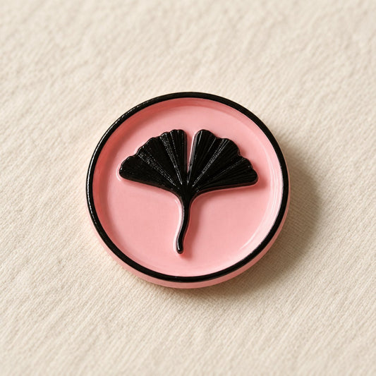 Detalle de un sello adhesivo rosa con hoja de ginkgo y borde negro pintado a mano