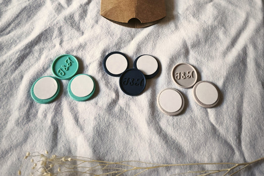Pack de prueba con iniciales Minimal: sellos adhesivos con las iniciales J&A en relieve, en turquesa, azul marino y arena, con sus dos sellos lisos de cada color