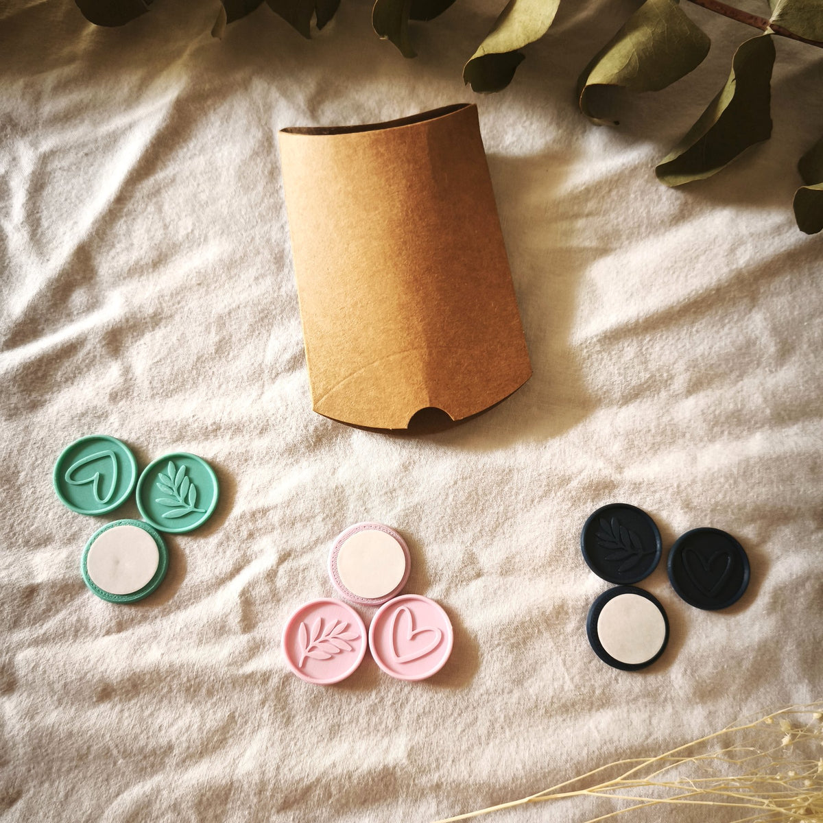 Pack de prueba Minimal: nueve sellos adhesivos en turquesa, rosa y azul marino, con corazón, rama y reverso adhesivo, junto a la caja kraft