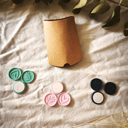 Pack de prueba Minimal: nueve sellos adhesivos en turquesa, rosa y azul marino, con corazón, rama y reverso adhesivo, junto a la caja kraft