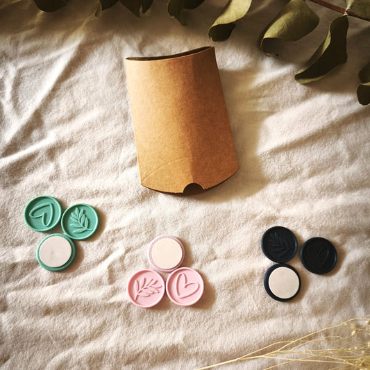 Pack de prueba Minimal: nueve sellos adhesivos en turquesa, rosa y azul marino, con corazón, rama y reverso adhesivo, junto a la caja kraft