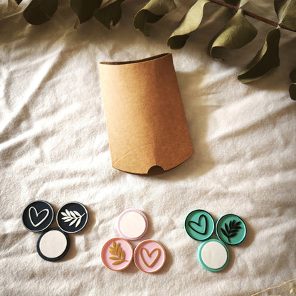 Pack de prueba Signature: nueve sellos adhesivos pintados a mano en azul marino y blanco, rosa y dorado, y turquesa y negro, junto a la caja kraft